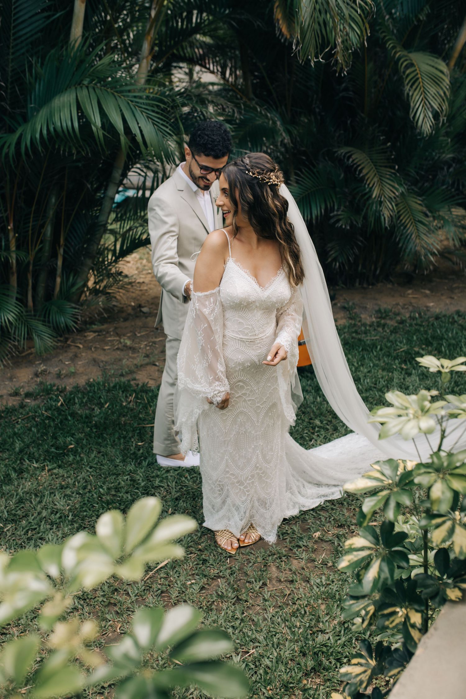 A tender moment between newlyweds in a tropical garden setting with flowing white dress and veil.