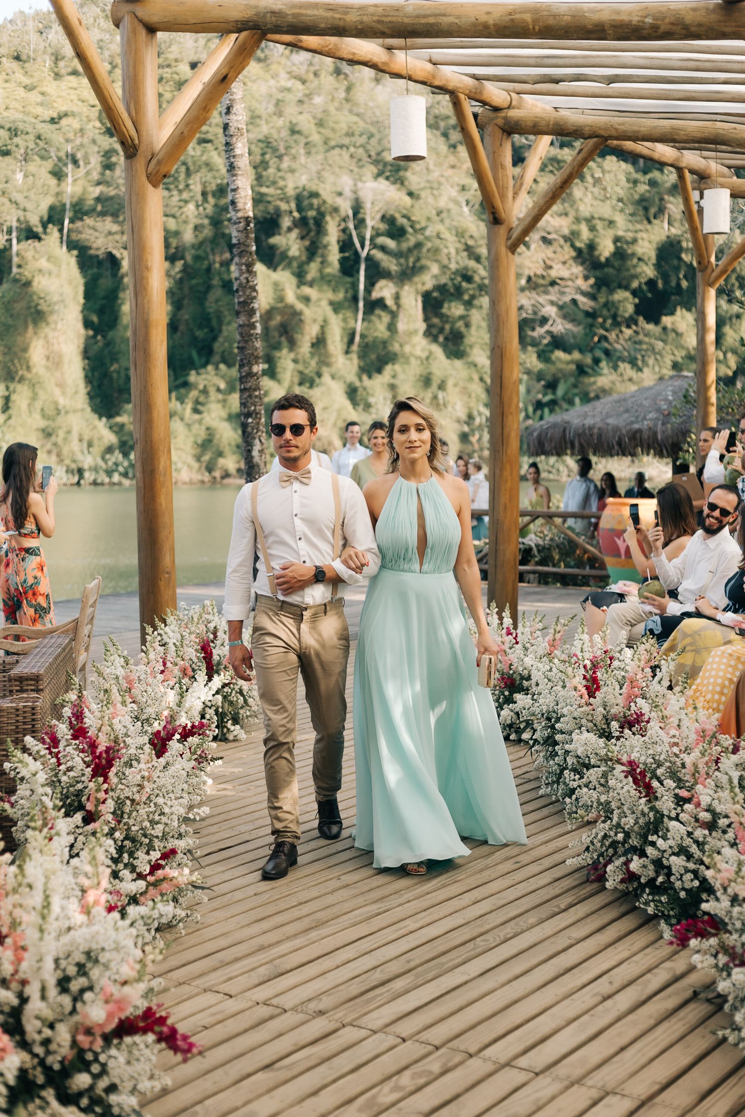 Formal event guests walking down decorated outdoor boardwalk with scenic mountain views.