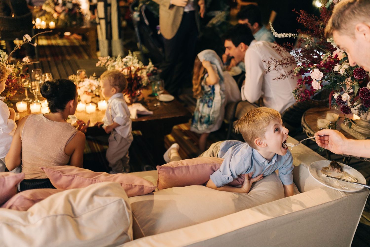 Children relax on cushions during evening wedding reception.