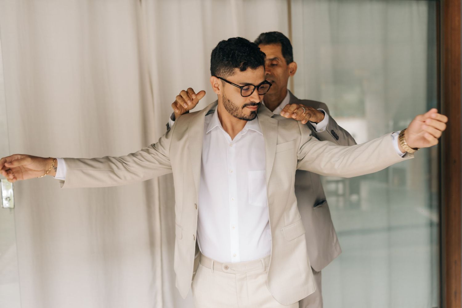 Person trying on light colored suit jacket with arms outstretched.