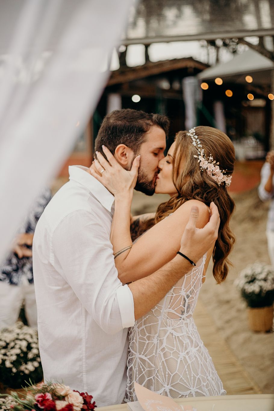 Romantic kiss shared between newlyweds at beachside wedding celebration.