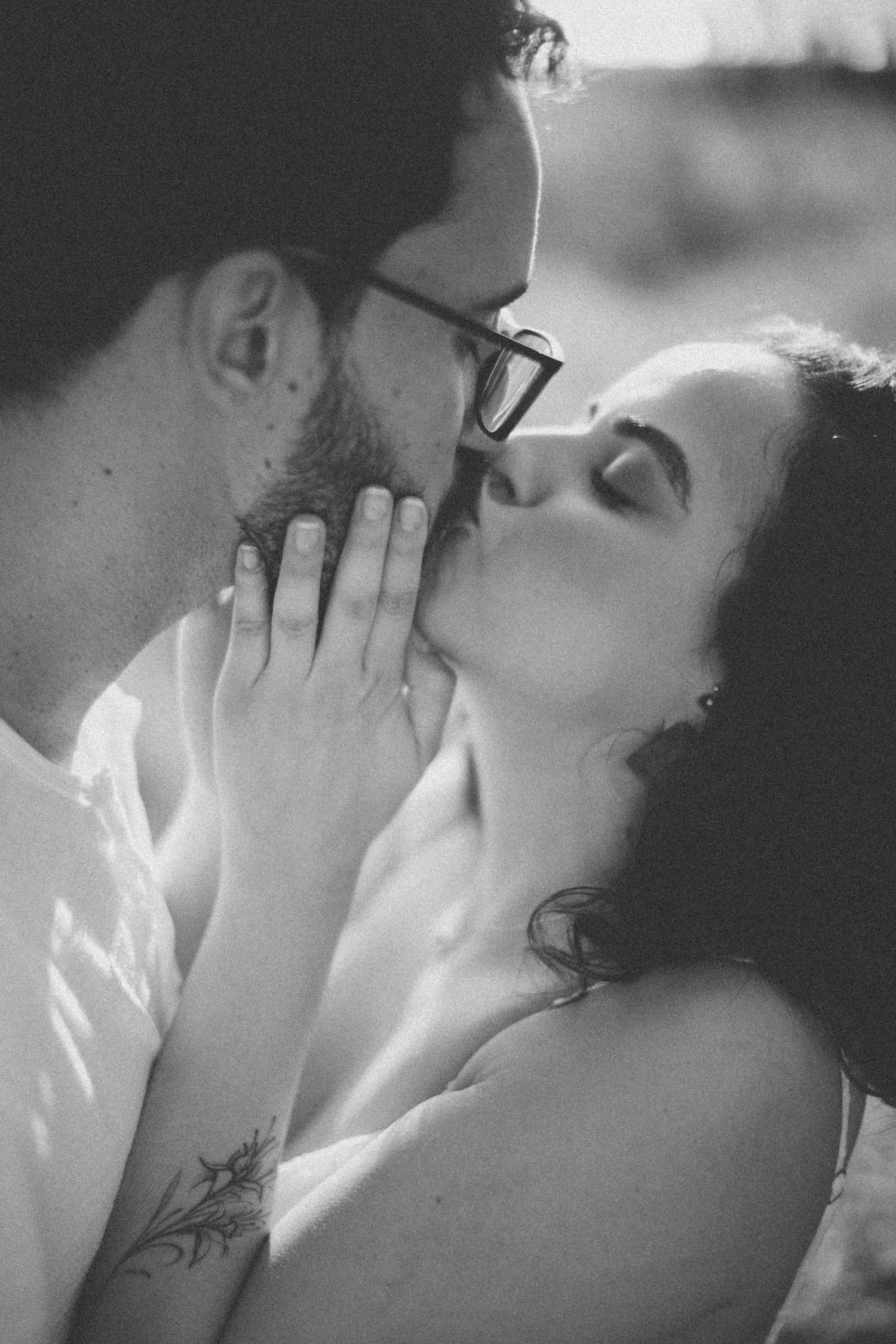 Intimate black and white portrait of a couple sharing a tender kiss.