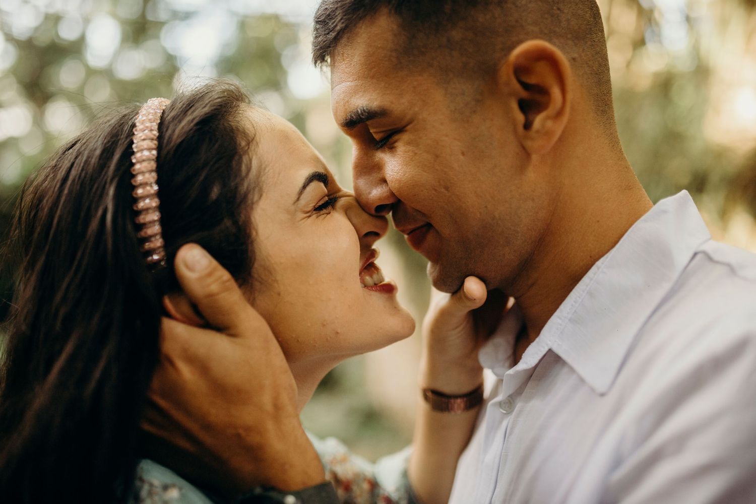 Close-up of couple sharing a joyful moment outdoors with bokeh background.