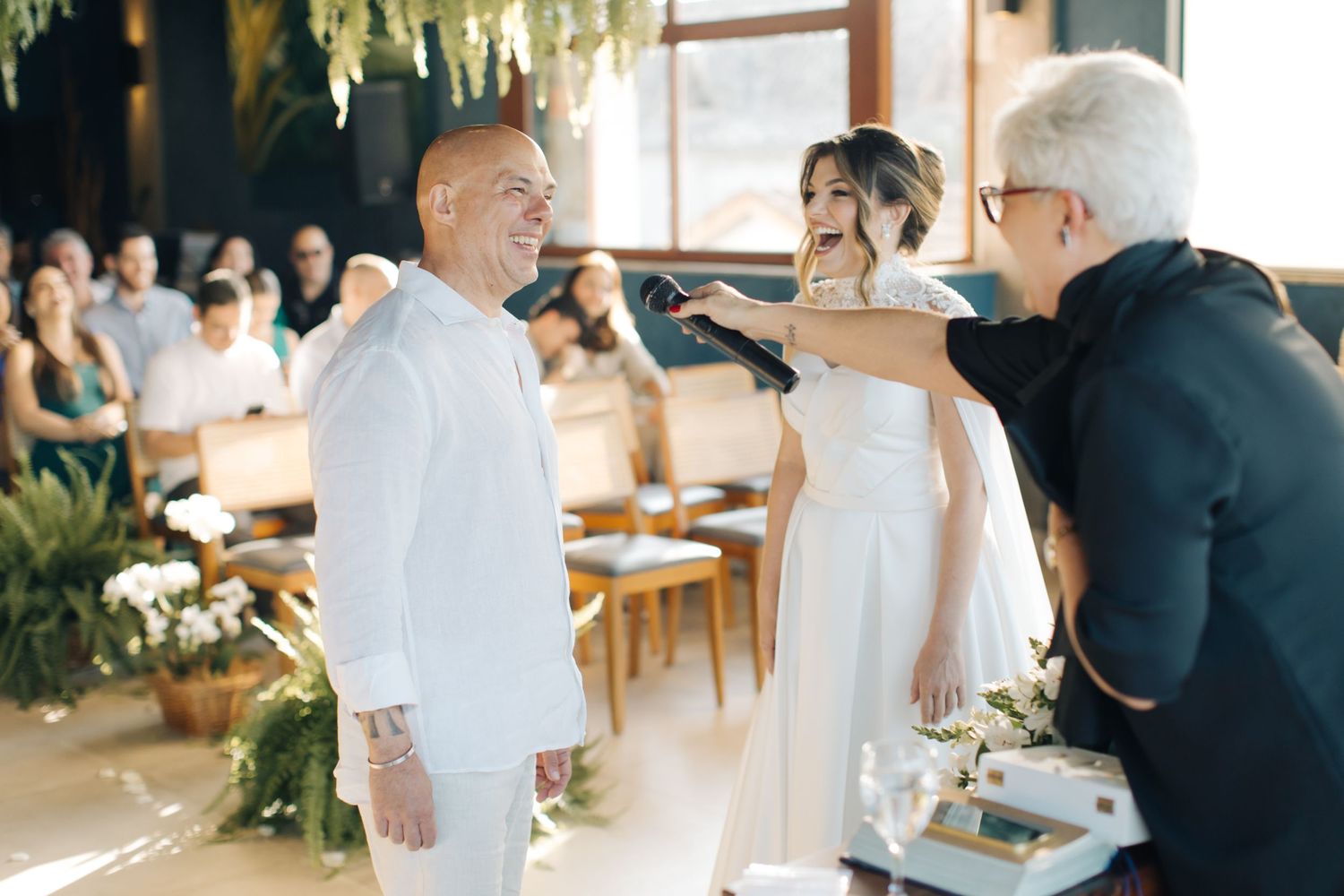 Wedding ceremony moments captured in bright natural light with hanging greenery decor.