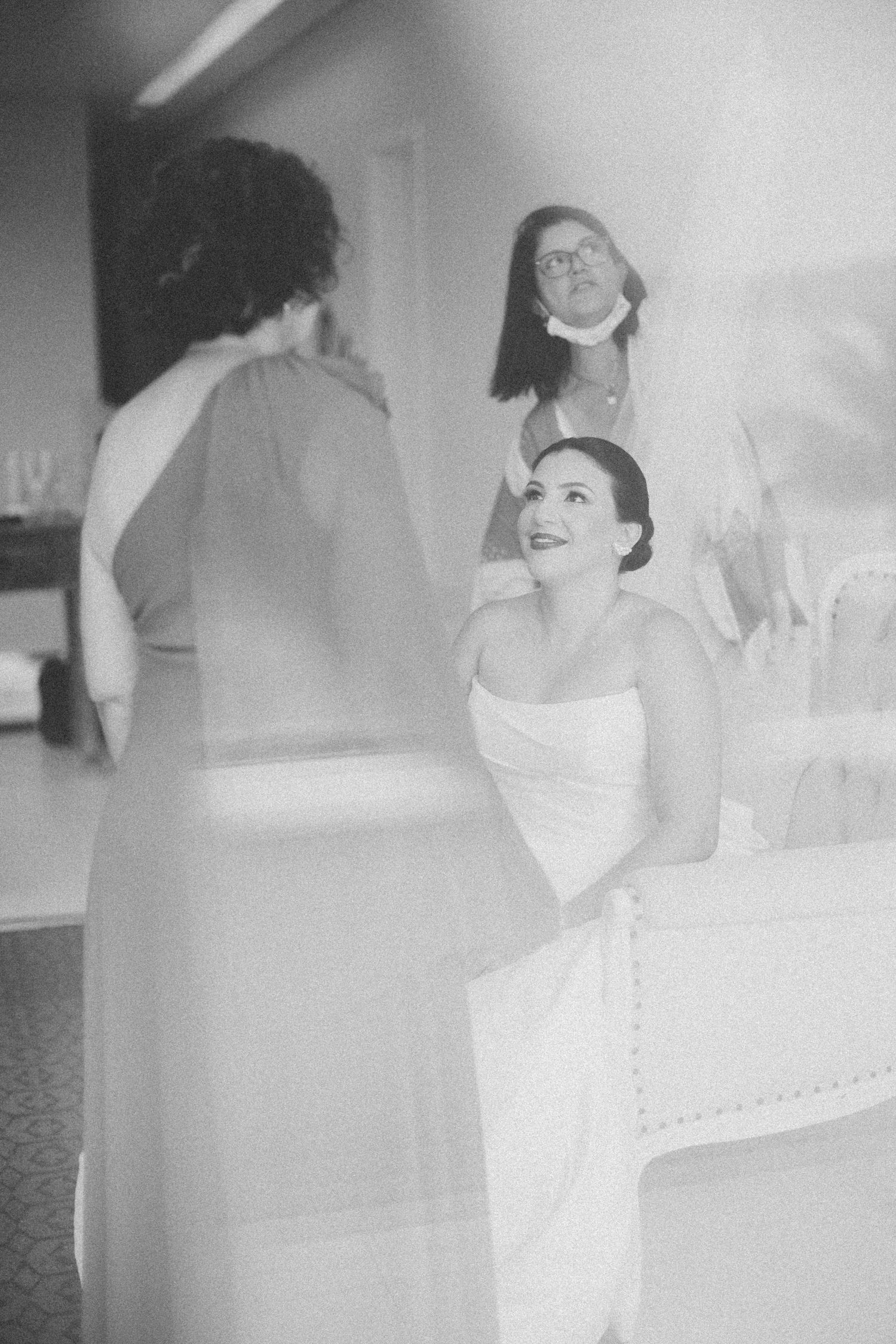Black and white candid moment of wedding preparation with laughter and joy.