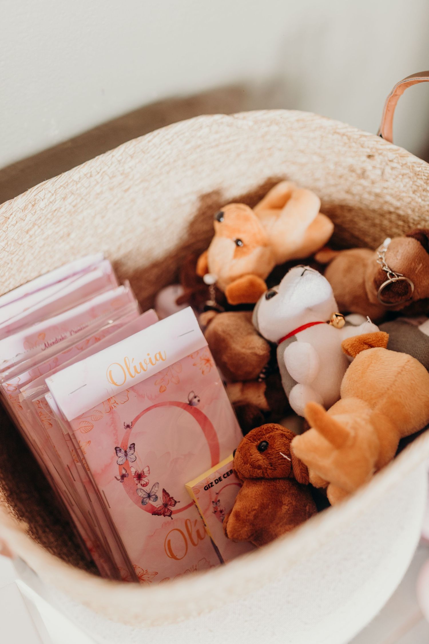 A collection of plush toys and pink books arranged in a white basket.