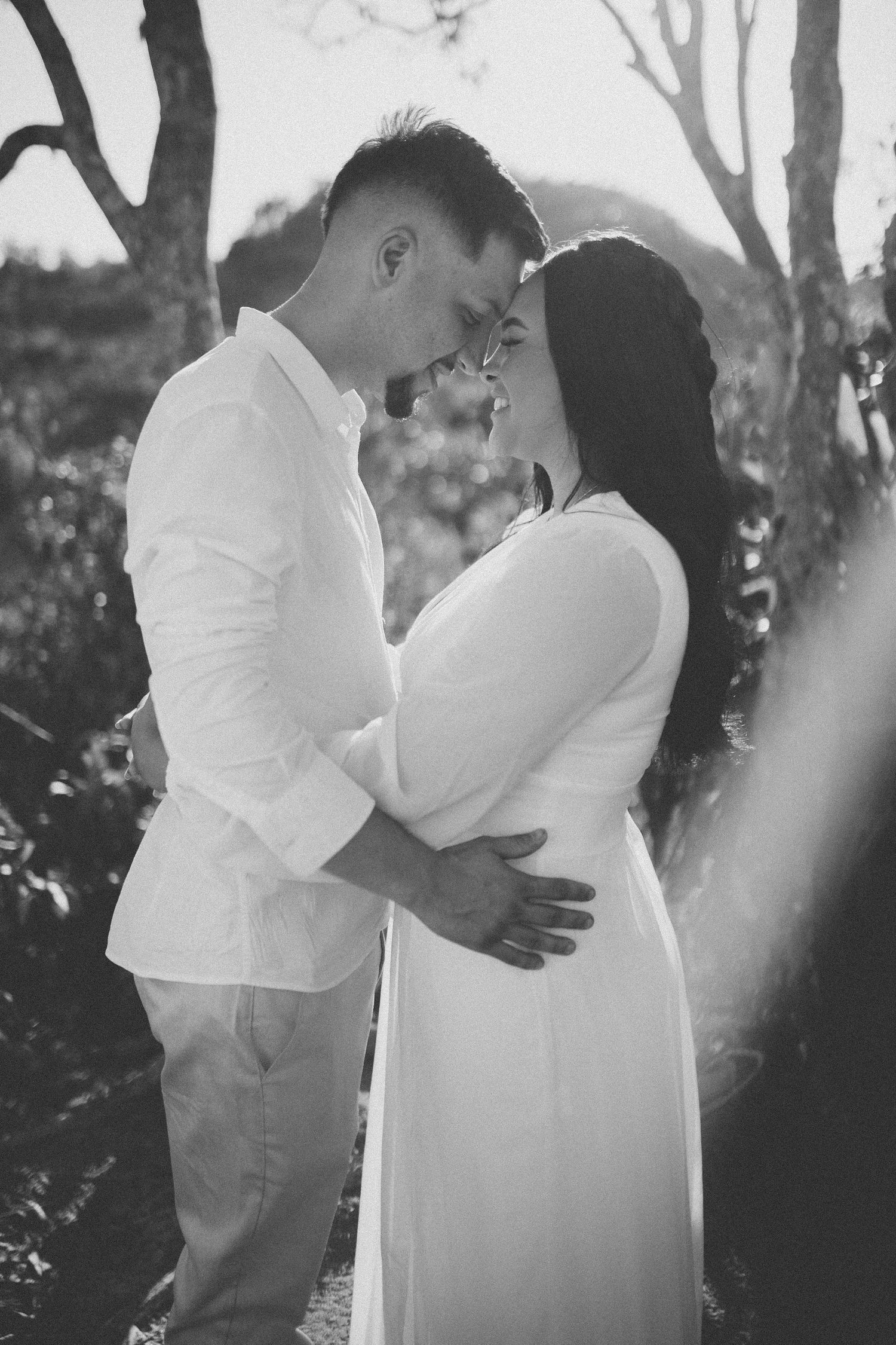 Black and white portrait of a couple embracing during an intimate outdoor photoshoot.