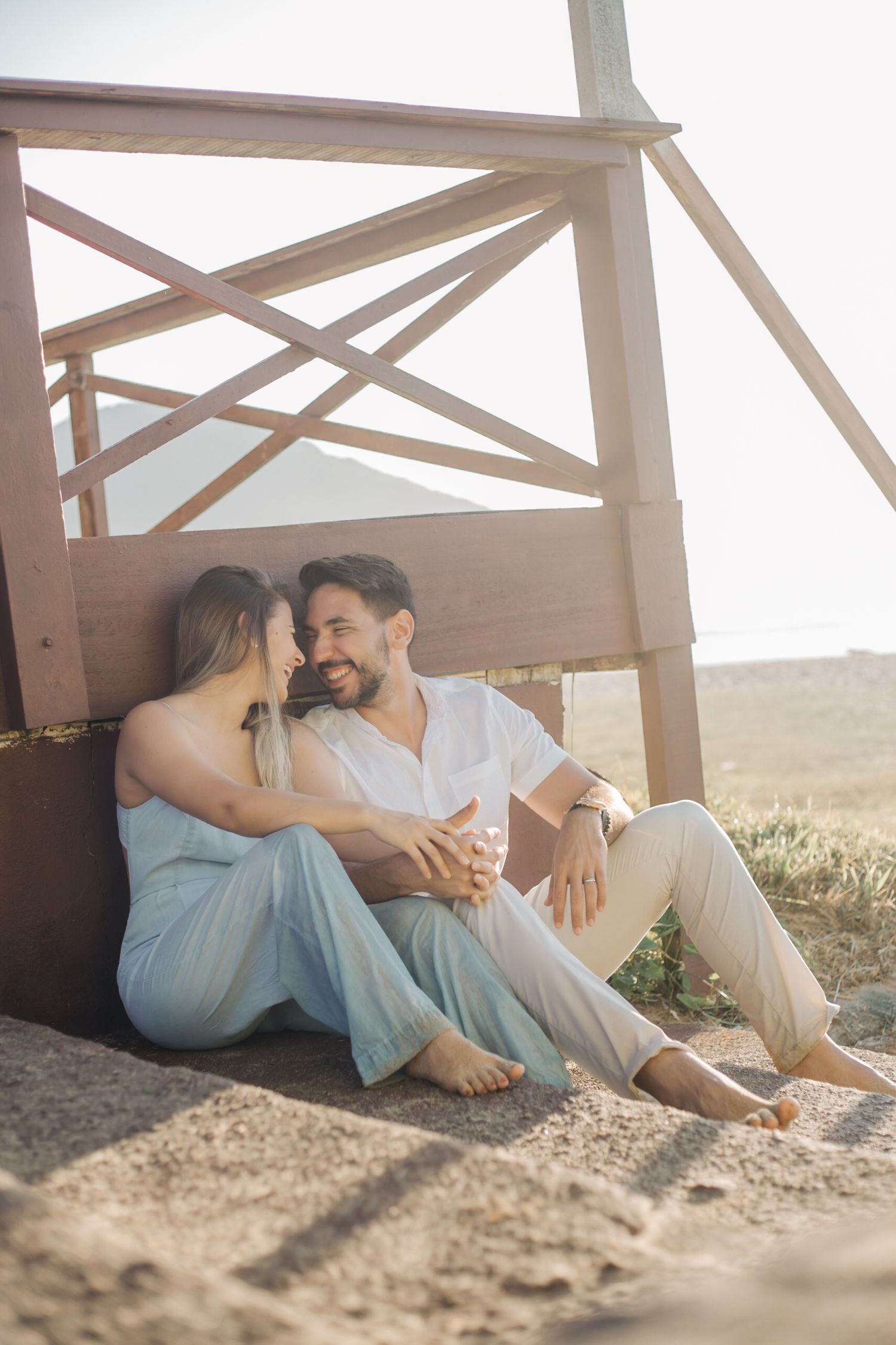 Loving couple sharing romantic moment while sitting on wooden deck with scenic view.