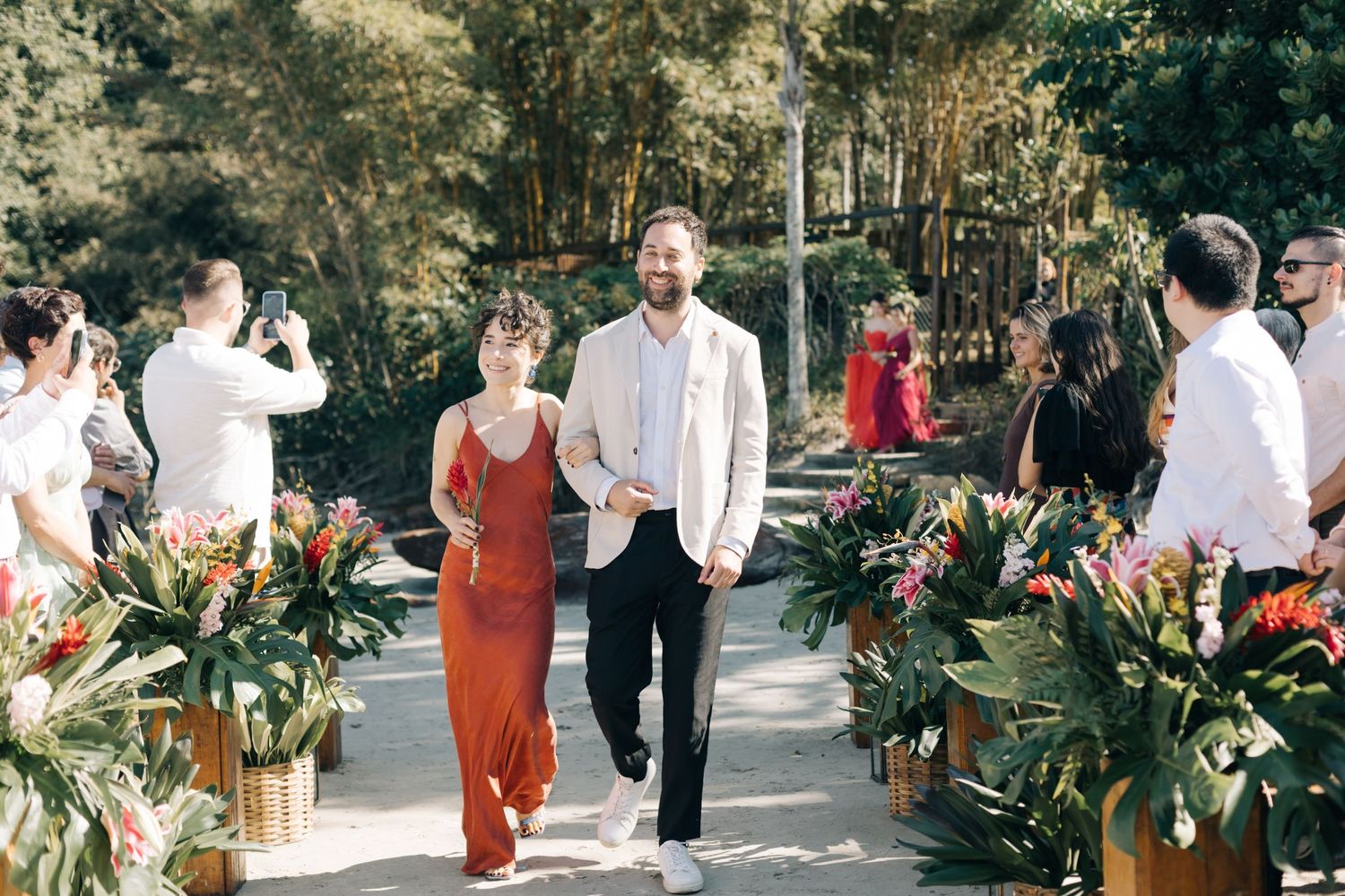 Wedding guests mingling at an outdoor reception with tropical floral decorations.