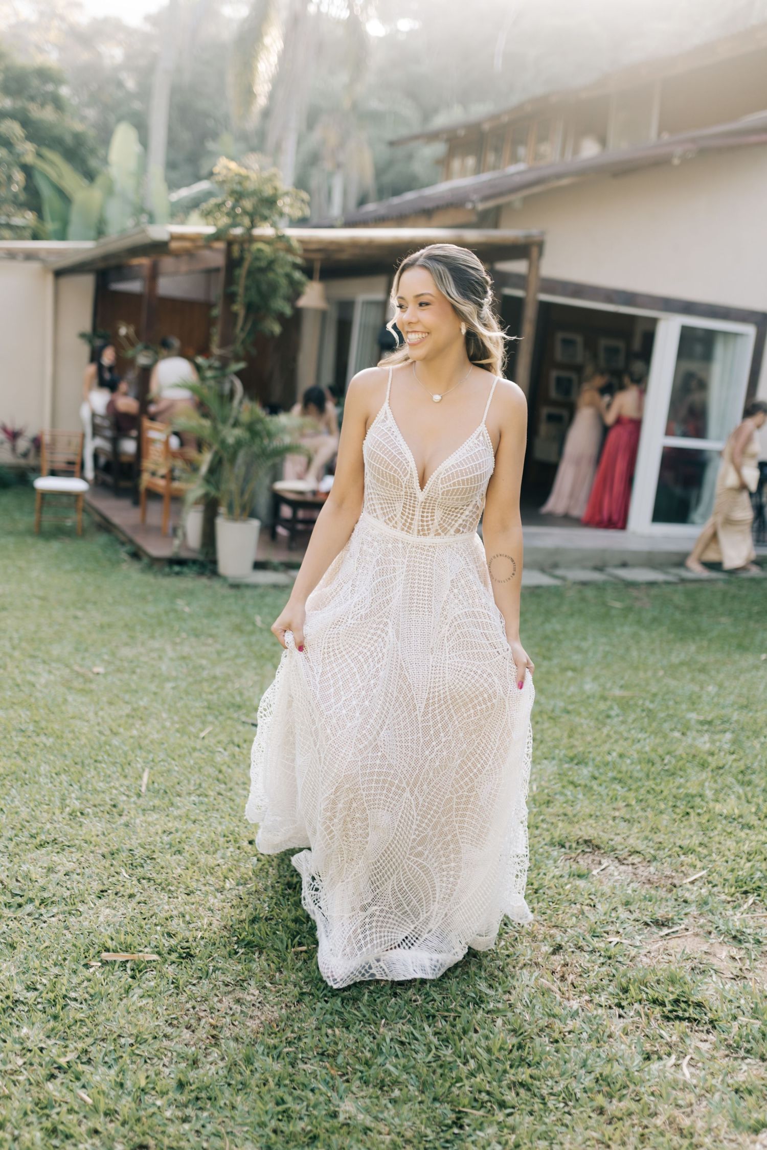 Bride showing movement of white lace wedding dress on lawn.