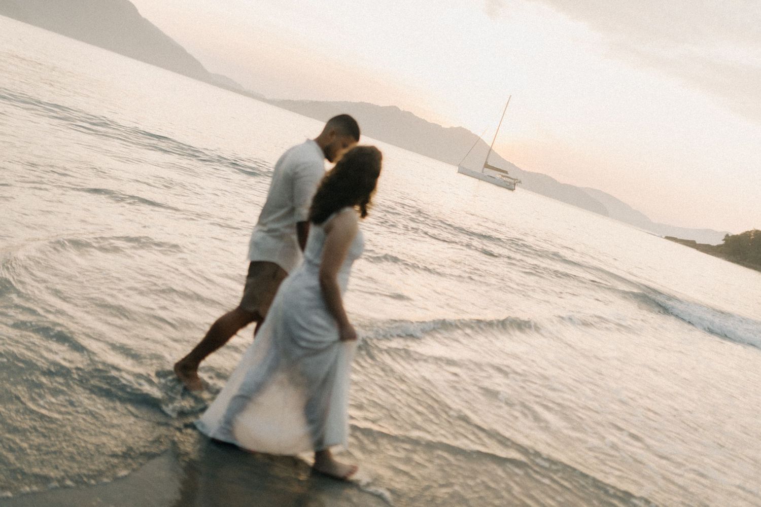 Couple walking and splashing through ocean waves at the beach.