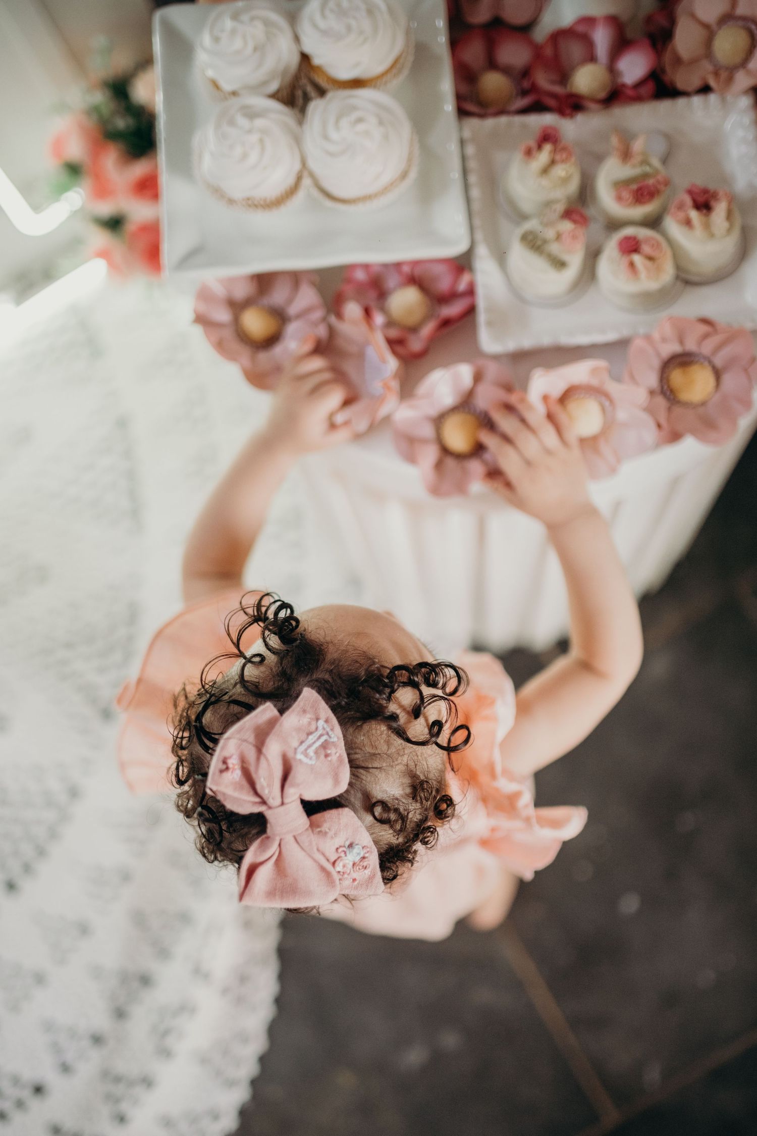 Top view of elegant pink party treats and decorations on a white tablecloth.