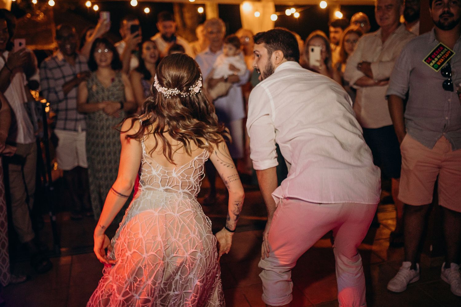 People dancing and celebrating at a lively wedding reception party with warm lighting and festive atmosphere.