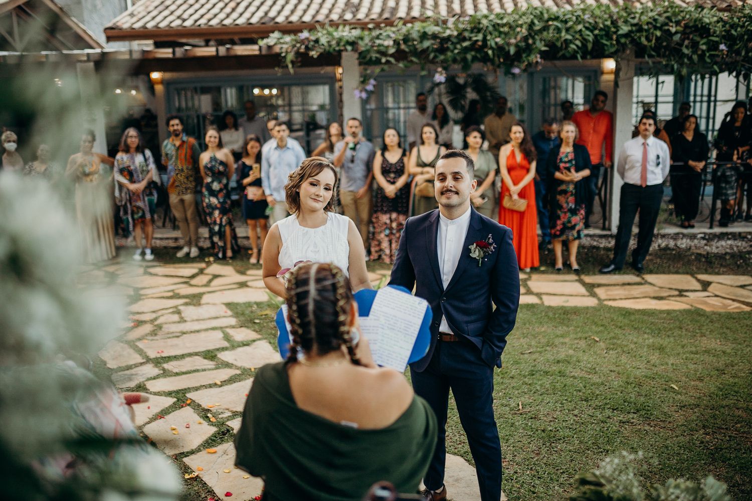 Guests mingle during an outdoor wedding reception under string lights and greenery.