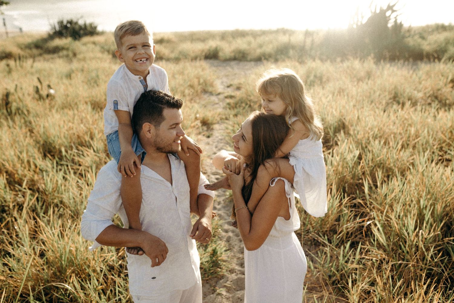 Candid moment of people in white clothing sharing laughter on a sunny beach.