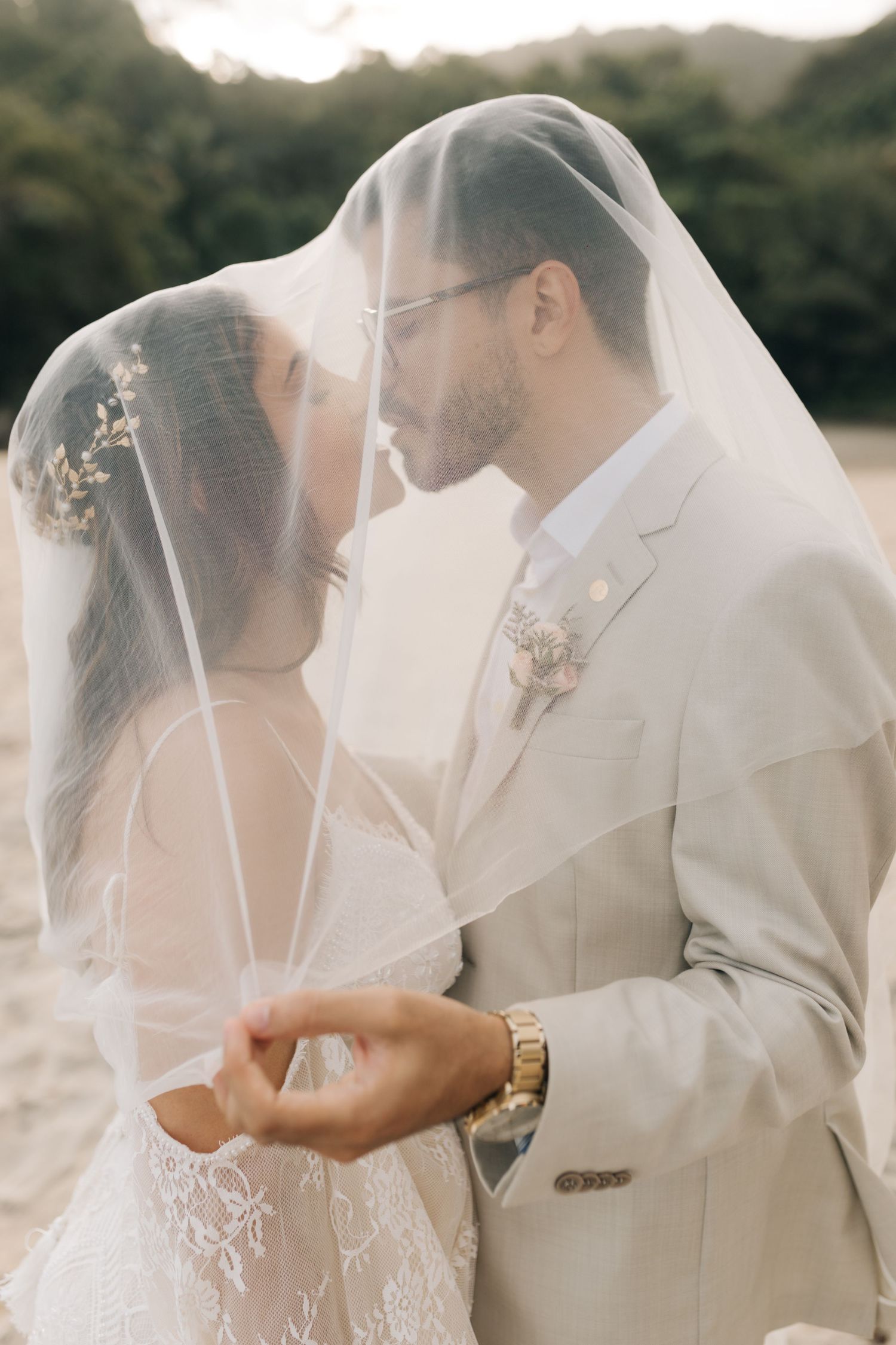 Intimate wedding portrait capturing tender moment between bride and groom under delicate veil.