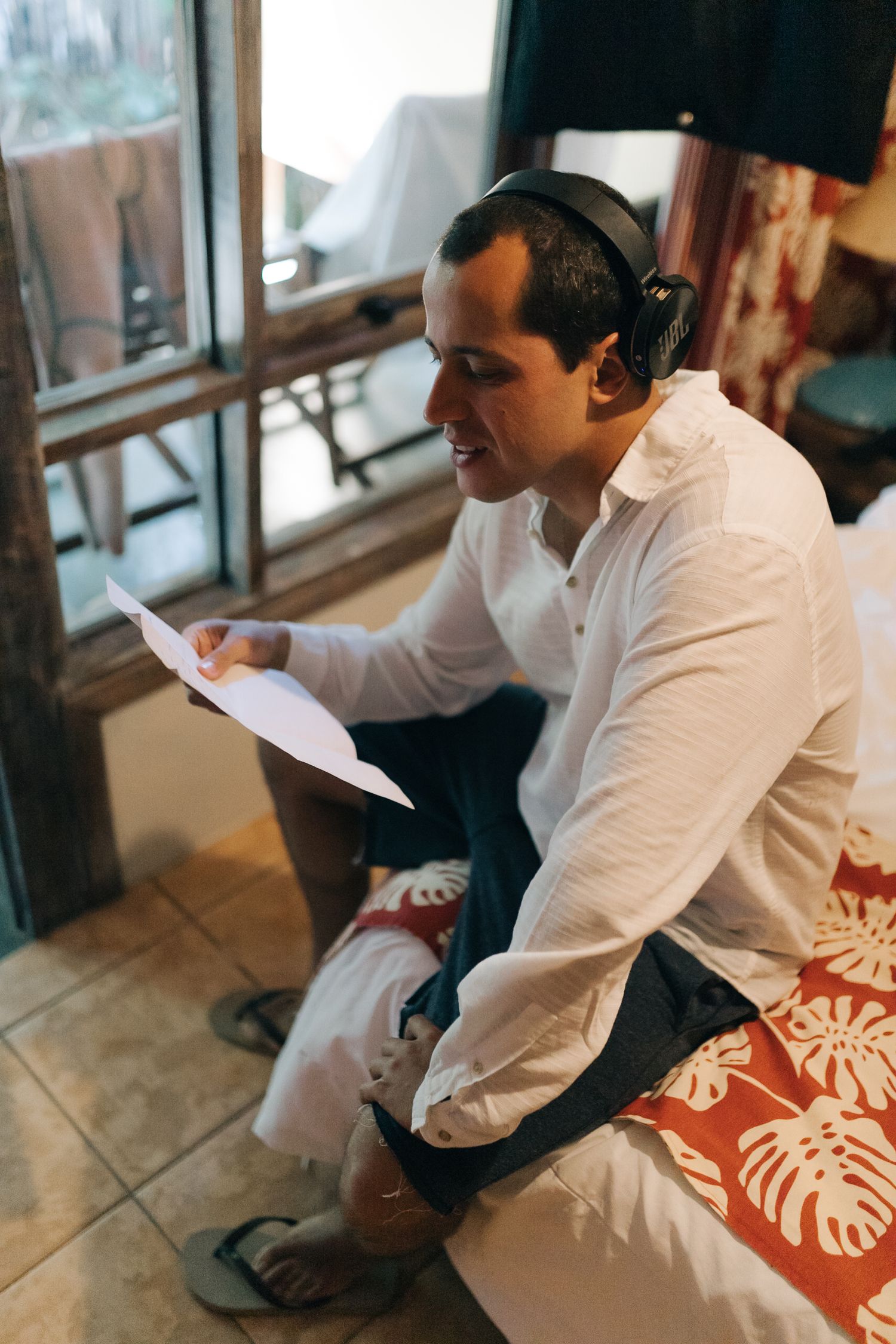 A person in white reviewing papers while seated in a casual indoor setting.