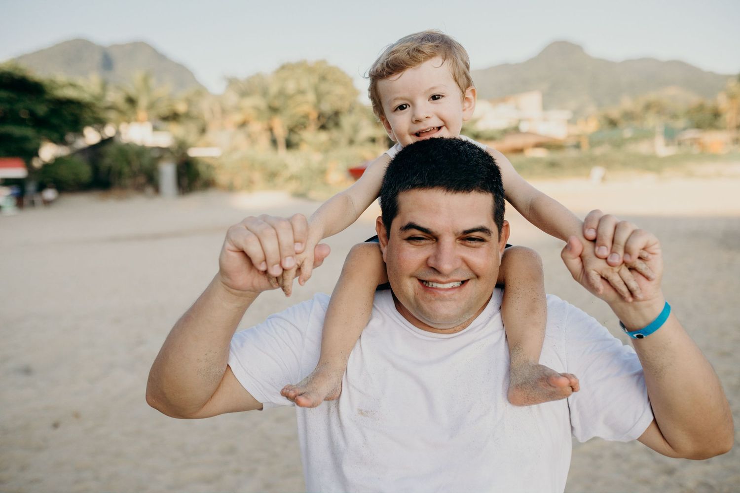 Cheerful beach portrait with mountains and coastal homes visible in the distance.