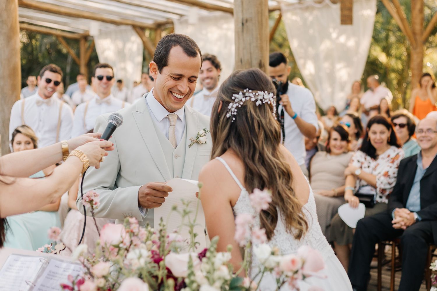 Emotional wedding ceremony moment captured under rustic wooden pergola with floral decor.
