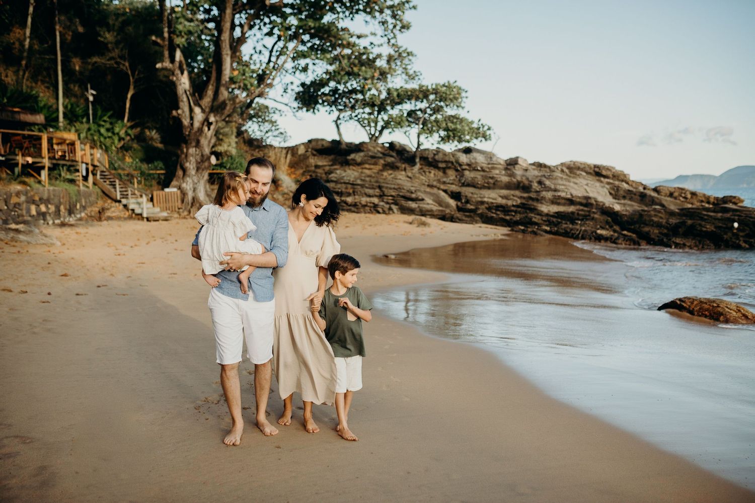 Family enjoying a peaceful moment together on a tropical beach at sunset.