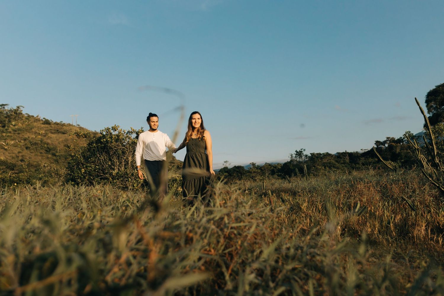 A couple walking together through a sun-drenched field.