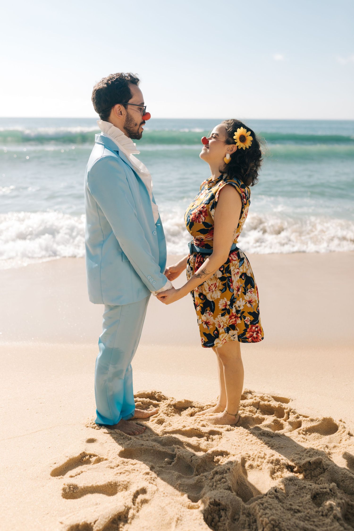 A couple shares a romantic moment on a sandy beach with crashing waves in the background.
