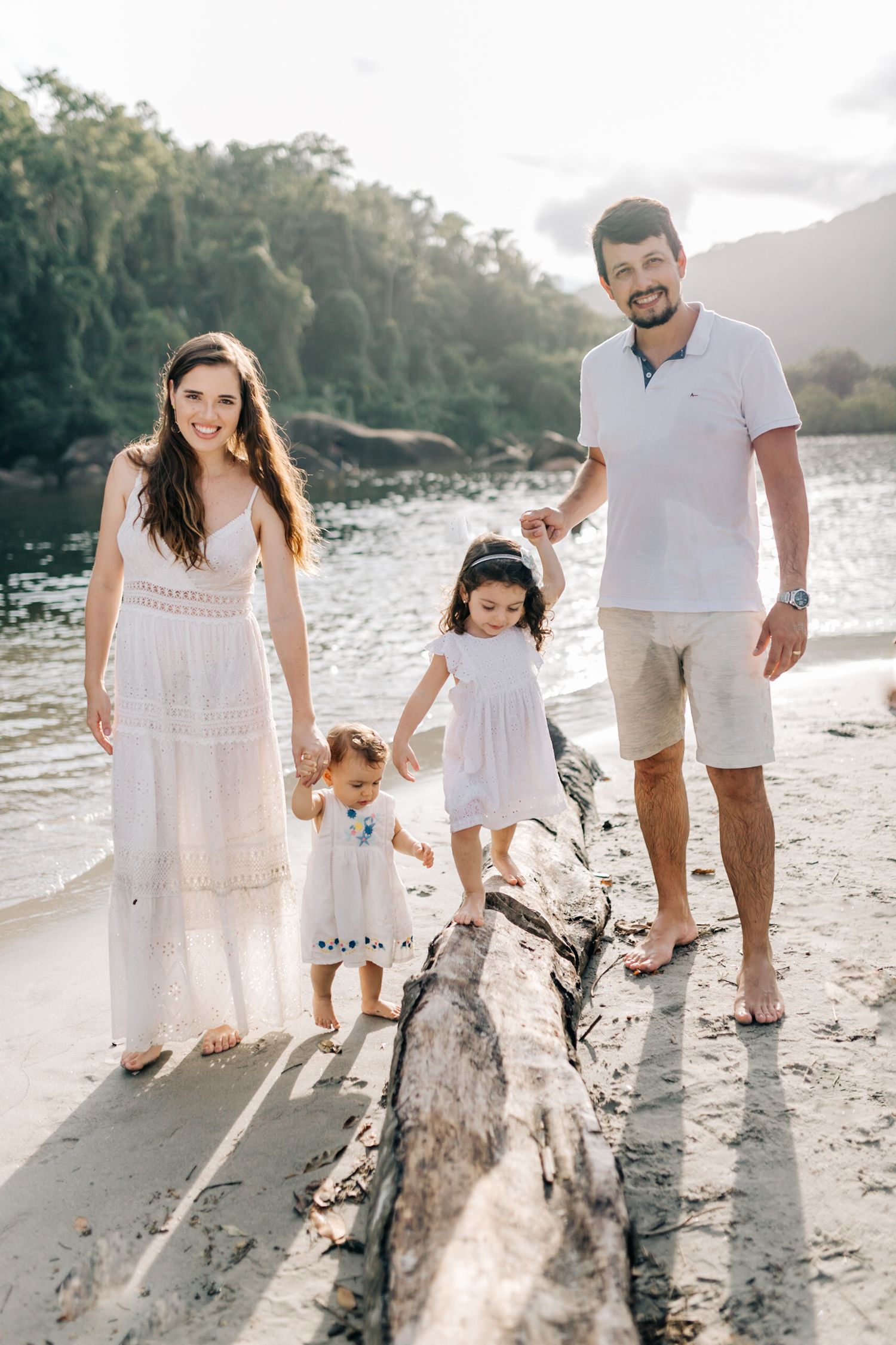 A family stands together on a beach log during a golden sunset photoshoot.