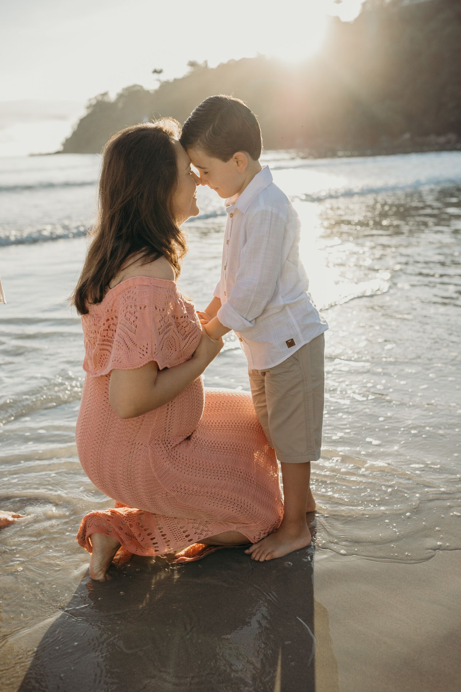 Sweet family interactions captured while sitting in shallow ocean waves at sunset.