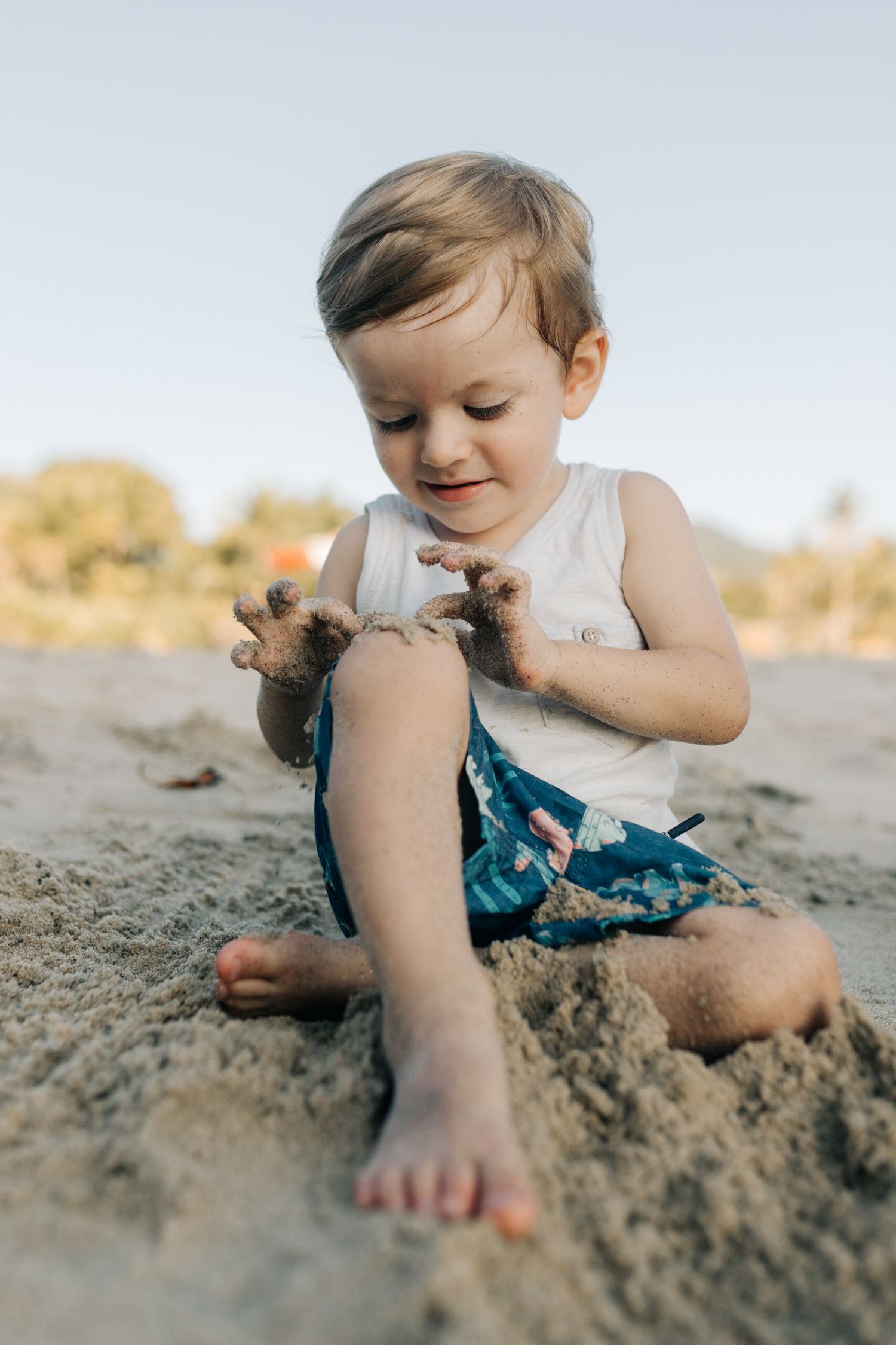 Child intently focuses on playing with sand during a beach day adventure.