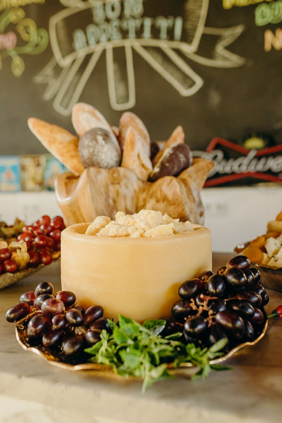 A gourmet appetizer plate featuring bread, grapes, and cheese with decorative chalkboard art in background.