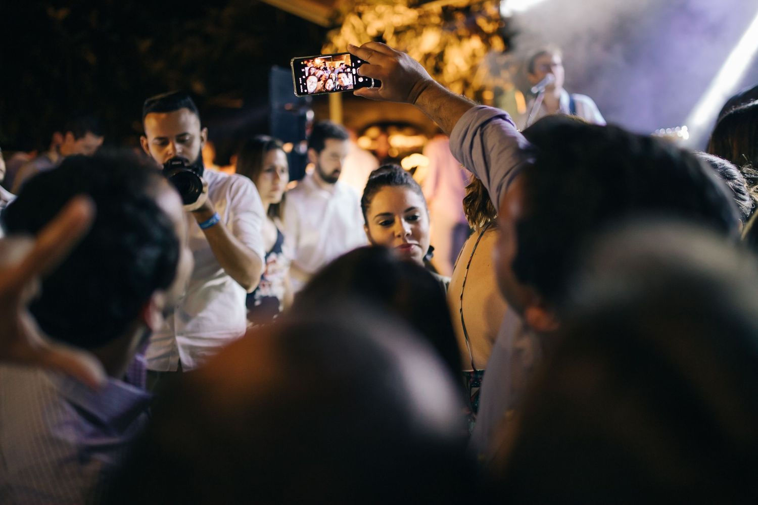 Crowded dance floor scene at a wedding reception with celebratory lighting and dancing guests.