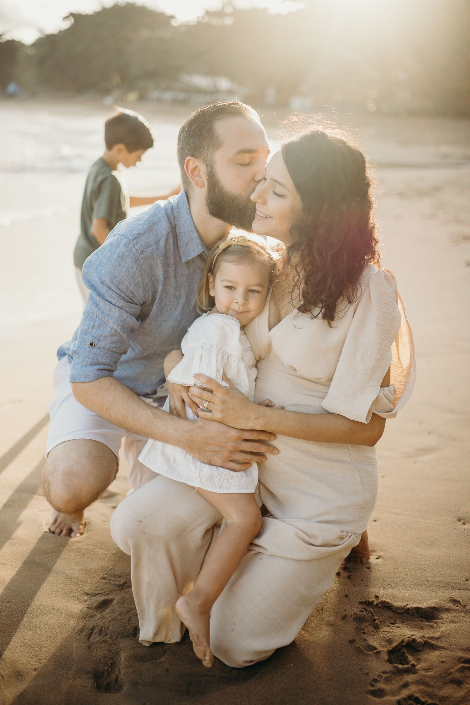 Emotional family beach photography with soft sunset lighting.