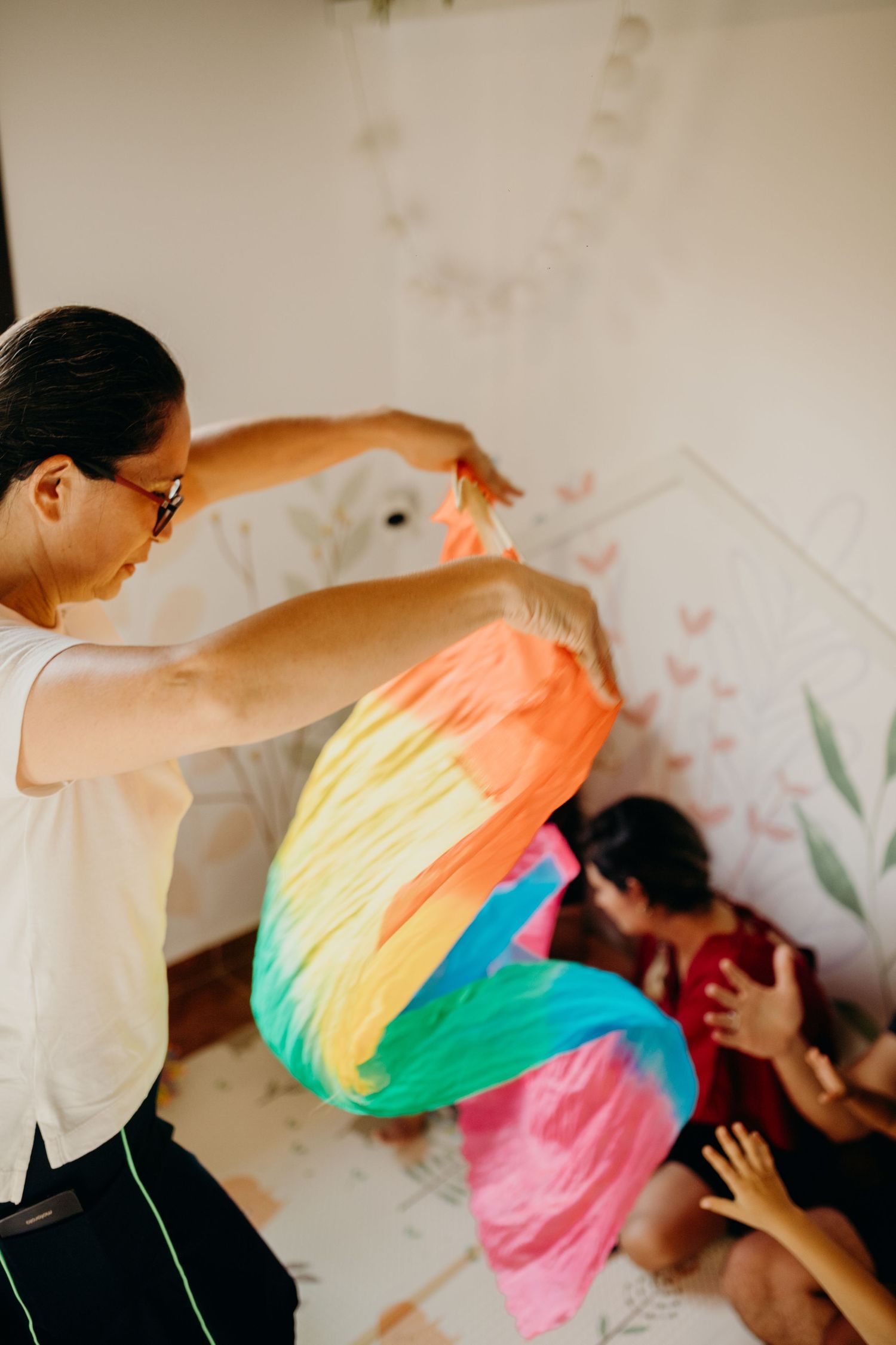 A person waves a rainbow-colored fabric during an interactive session.