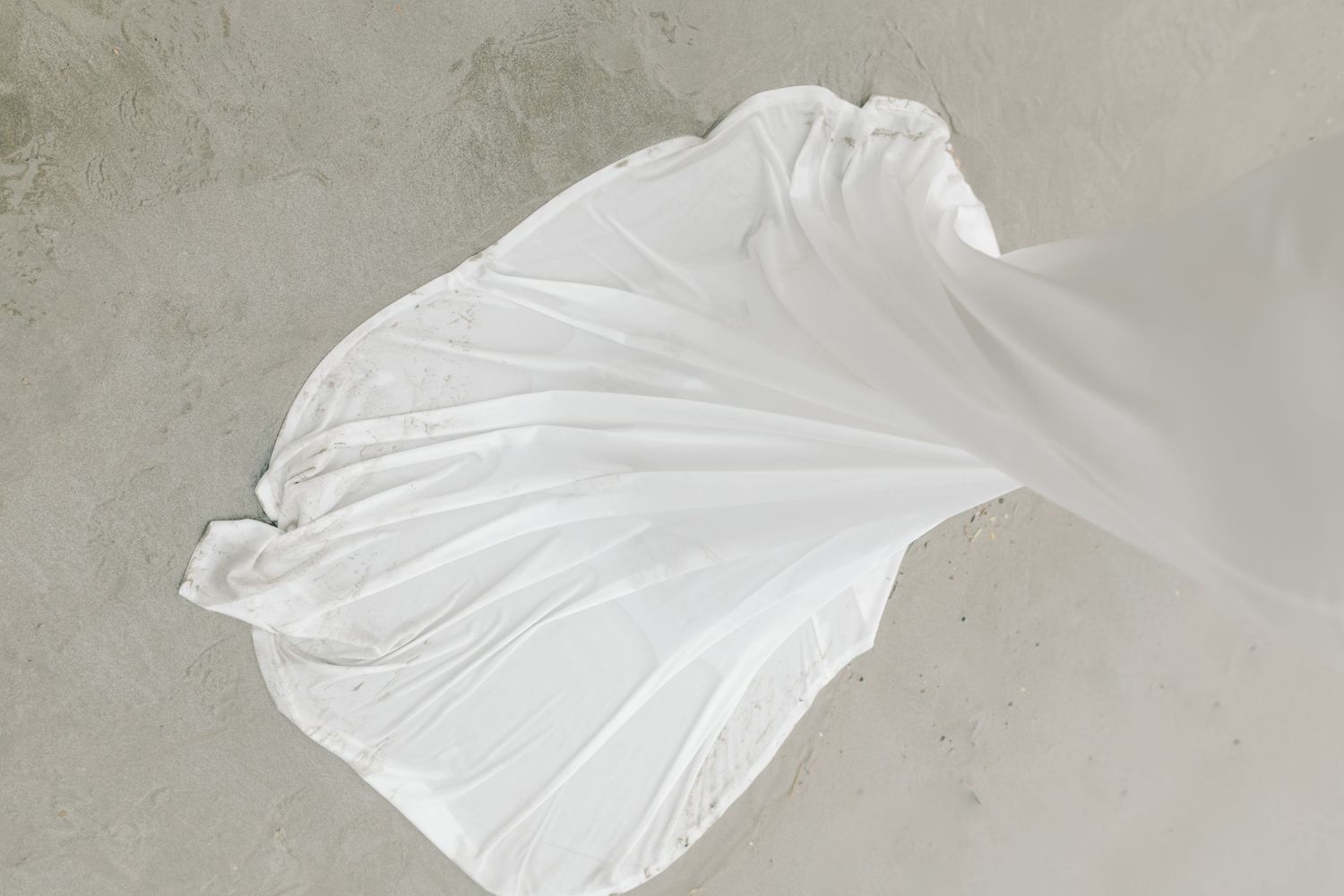 Billowing white fabric creates abstract pattern against light background.