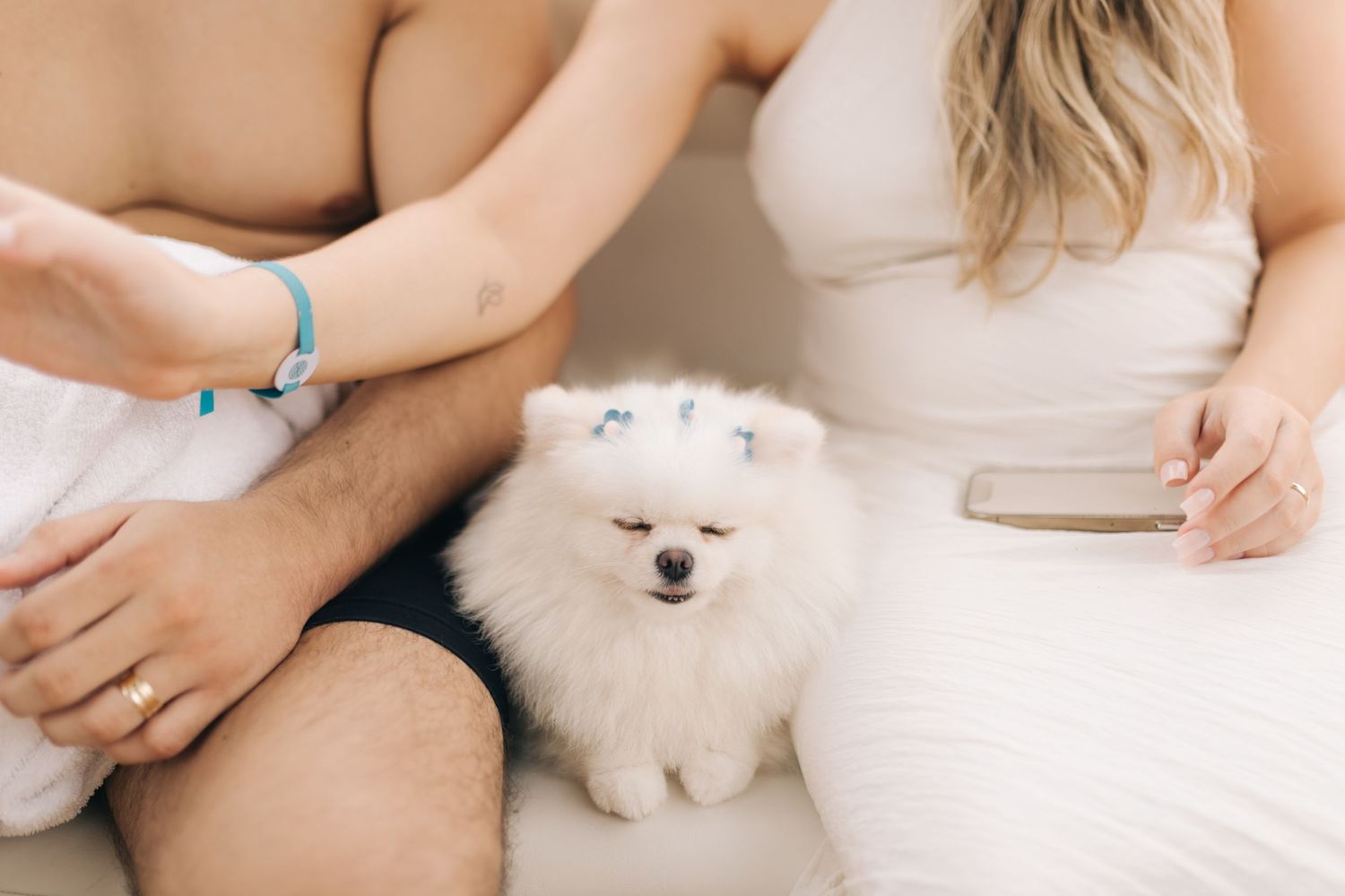 Couple relaxing on boat with small white Pomeranian dog between them.