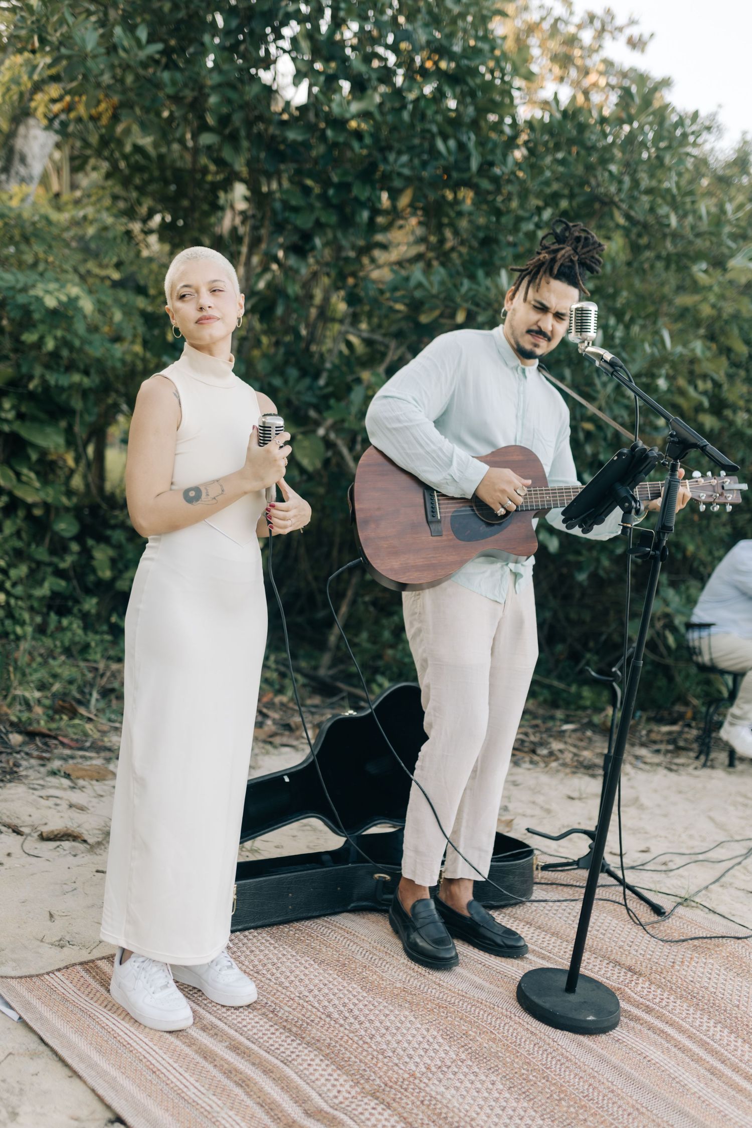Wedding musicians performing on a wooden platform with guitar and microphone.