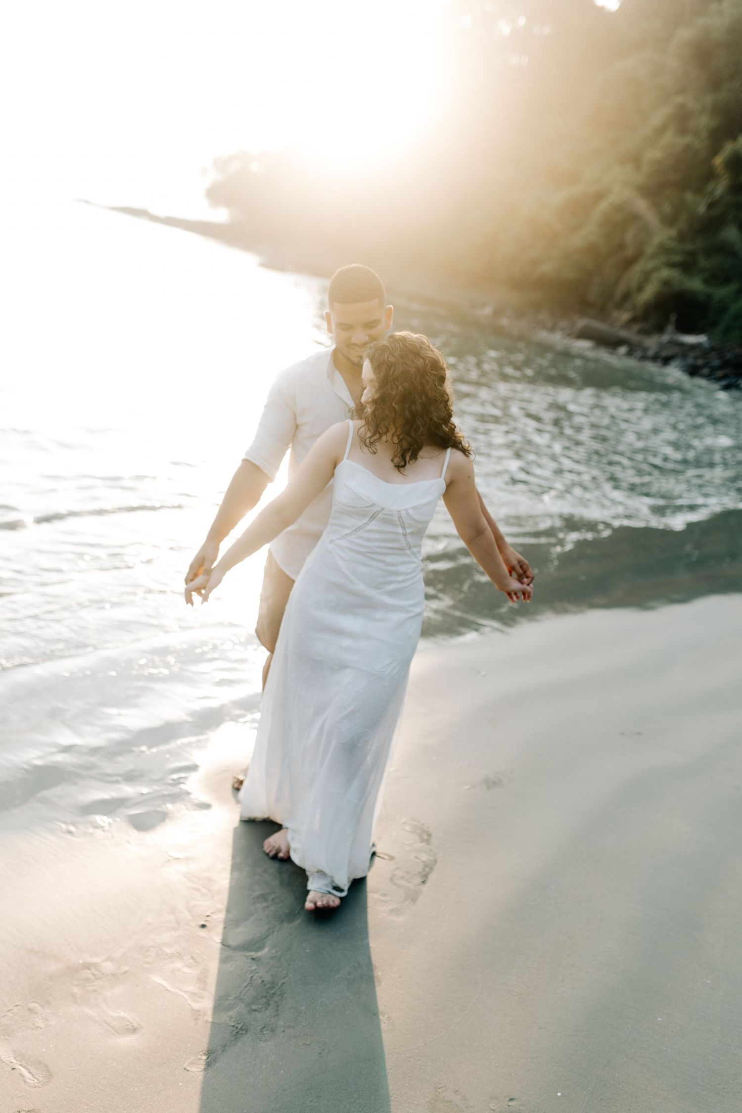 Couple leaving footprints in the sand during romantic beach photography session.