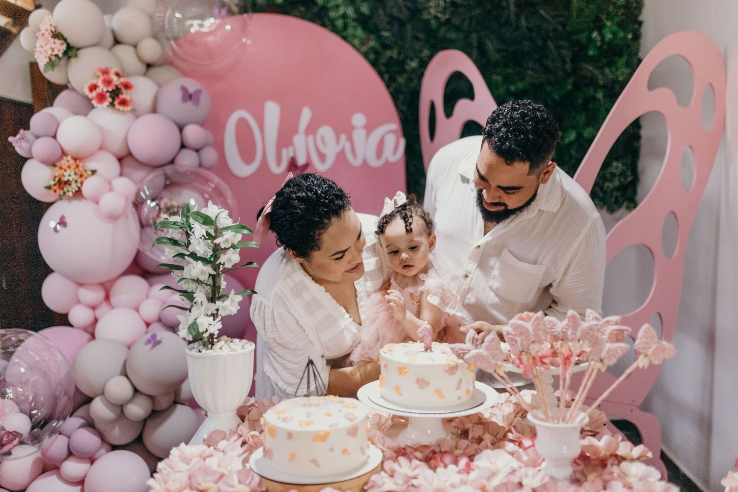 Birthday celebration with pink balloon arch and cake display.
