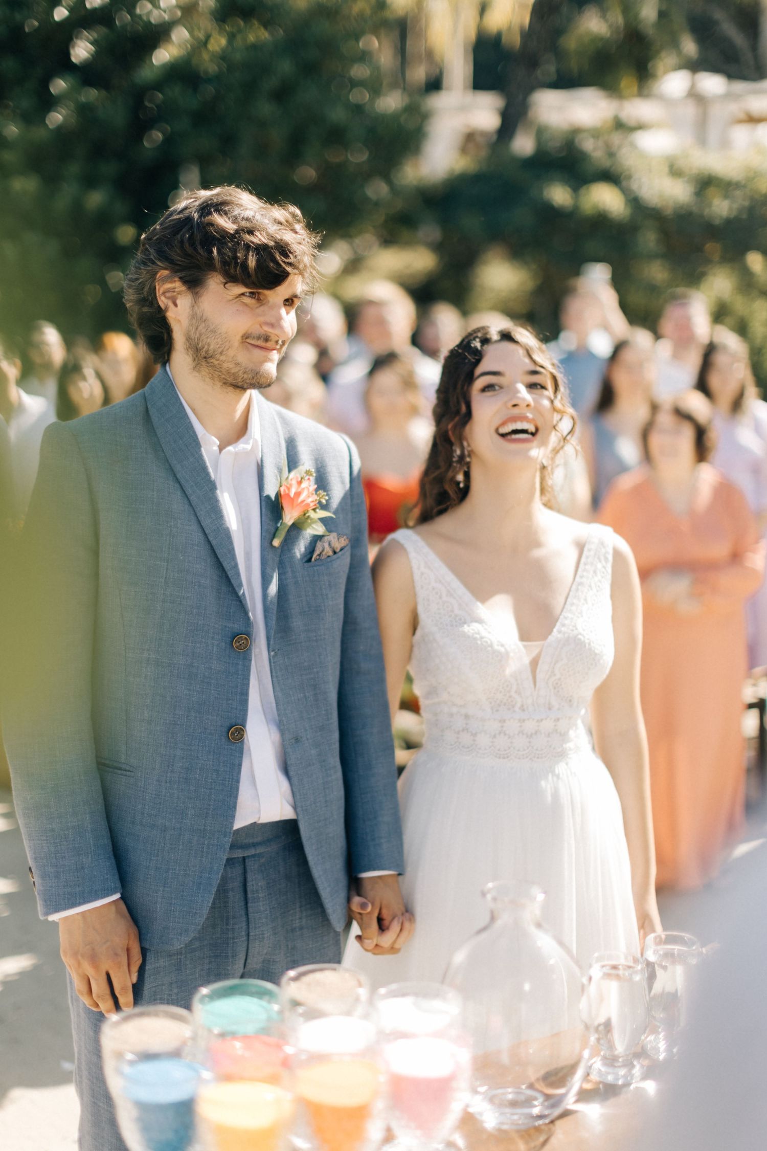 Newlyweds share a joyful moment next to colorful drinks at their outdoor reception.