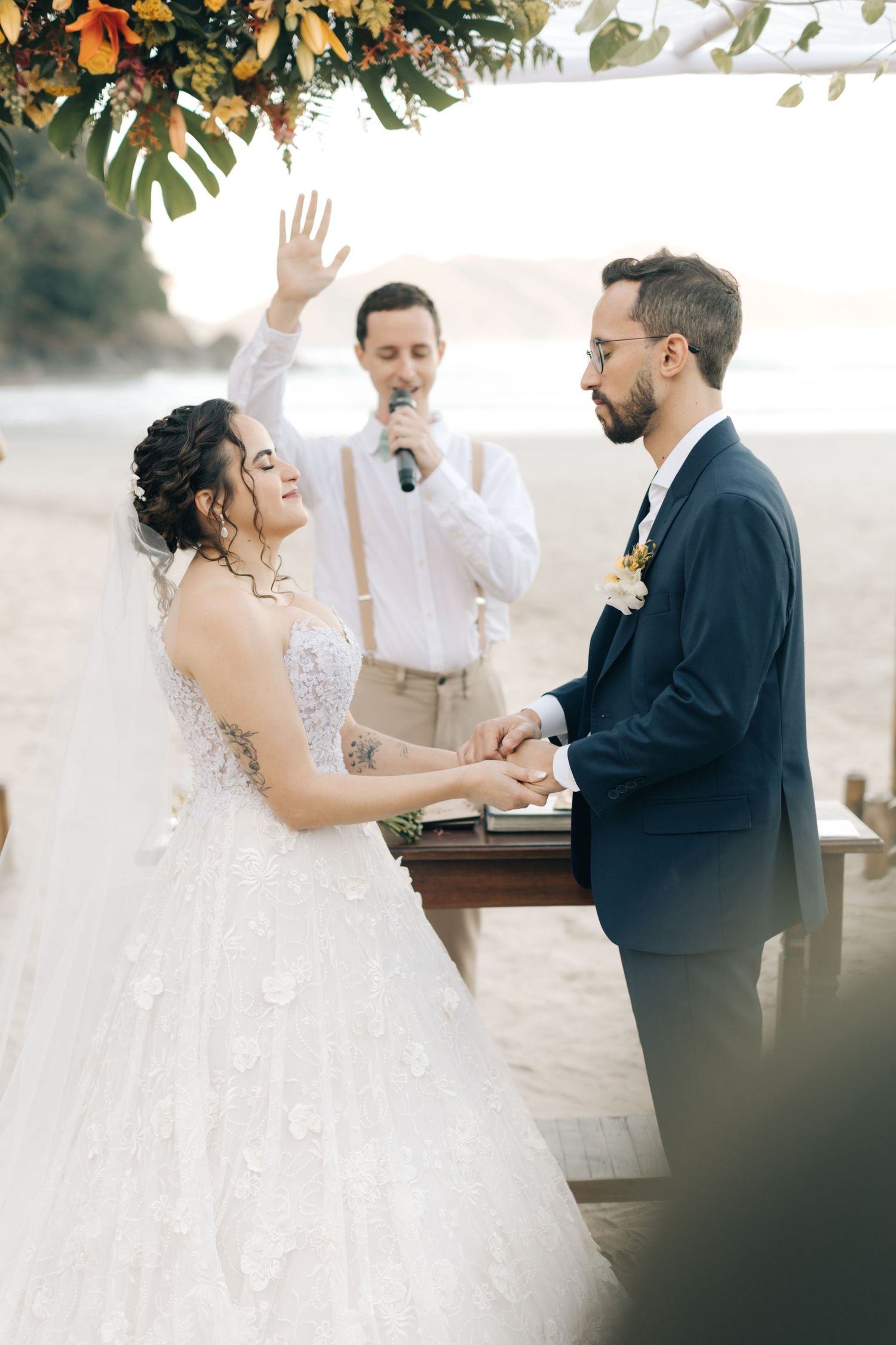 Romantic wedding ceremony moments captured on a beach with tropical floral decorations.