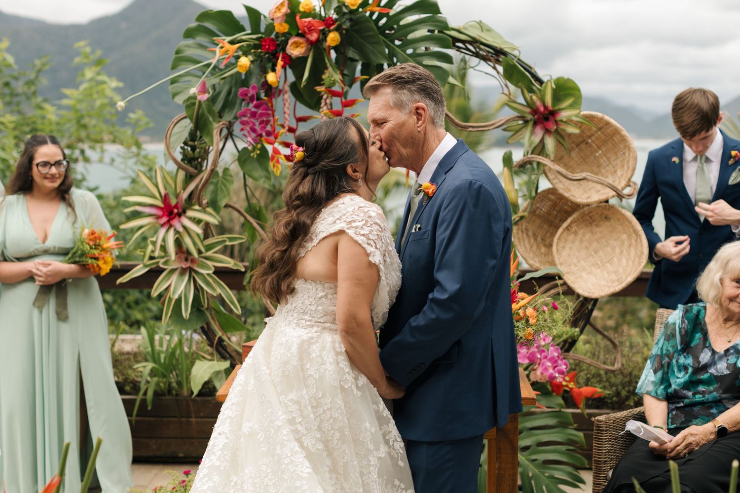 Wedding ceremony setup with tropical flowers and greenery against a mountain backdrop.