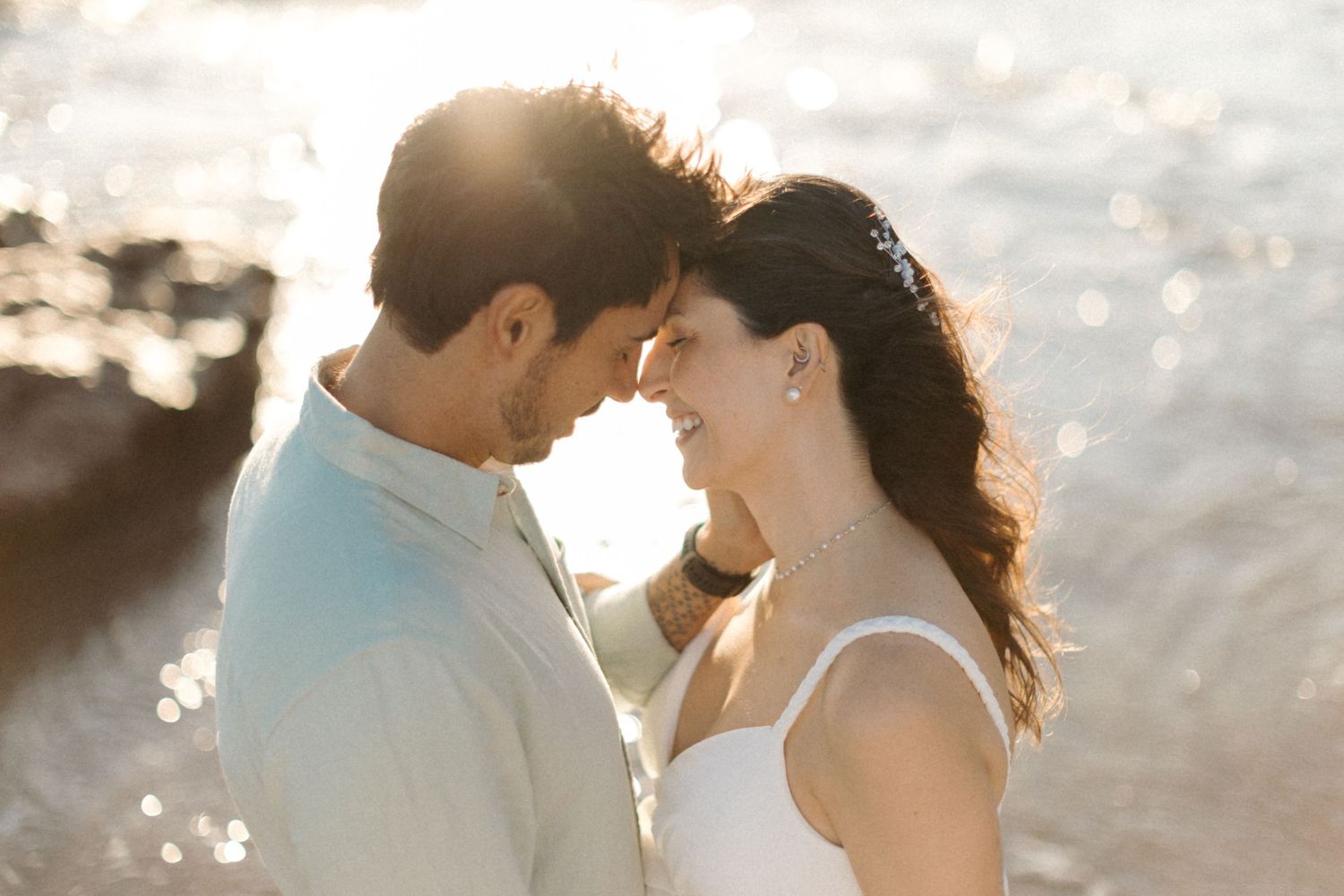 Intimate couple embracing during golden hour with sunlight creating a dreamy backlit effect.