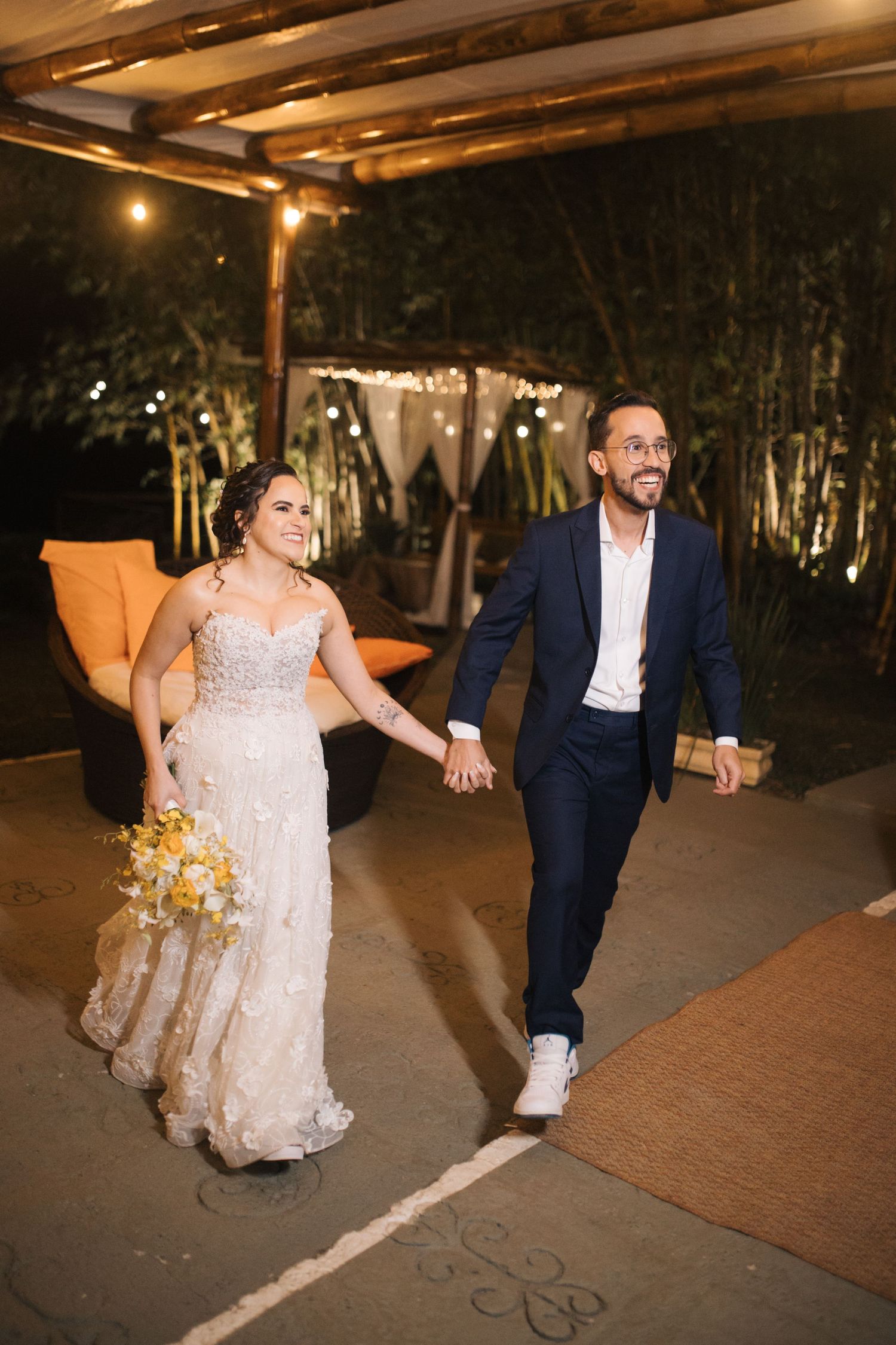 A couple dances beneath string lights at an outdoor wedding venue.