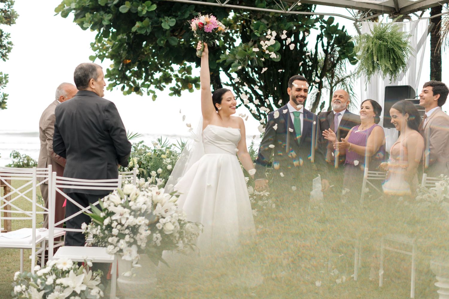 Outdoor wedding ceremony setup with white chairs and tropical garden backdrop.