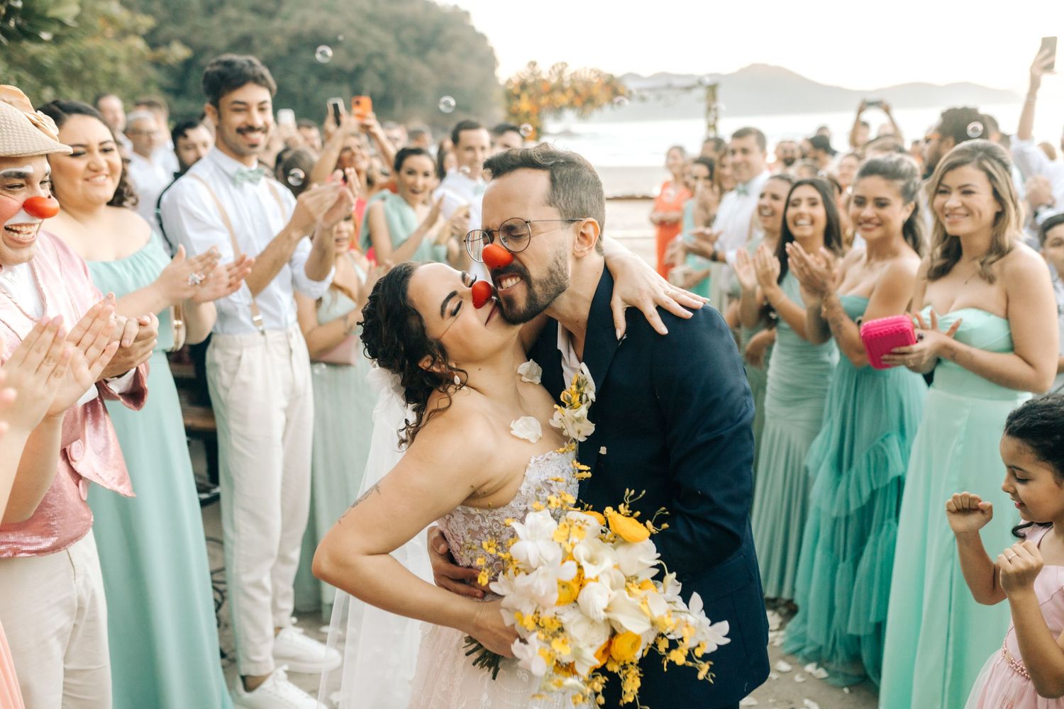 An intimate beach wedding celebration with cheerful guests and vibrant yellow bouquet.