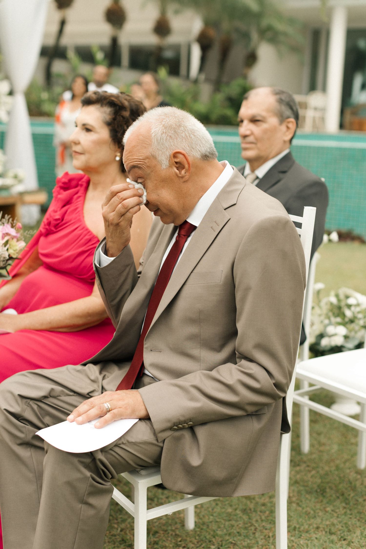 Wedding guests seated in white chairs enjoying the outdoor ceremony.