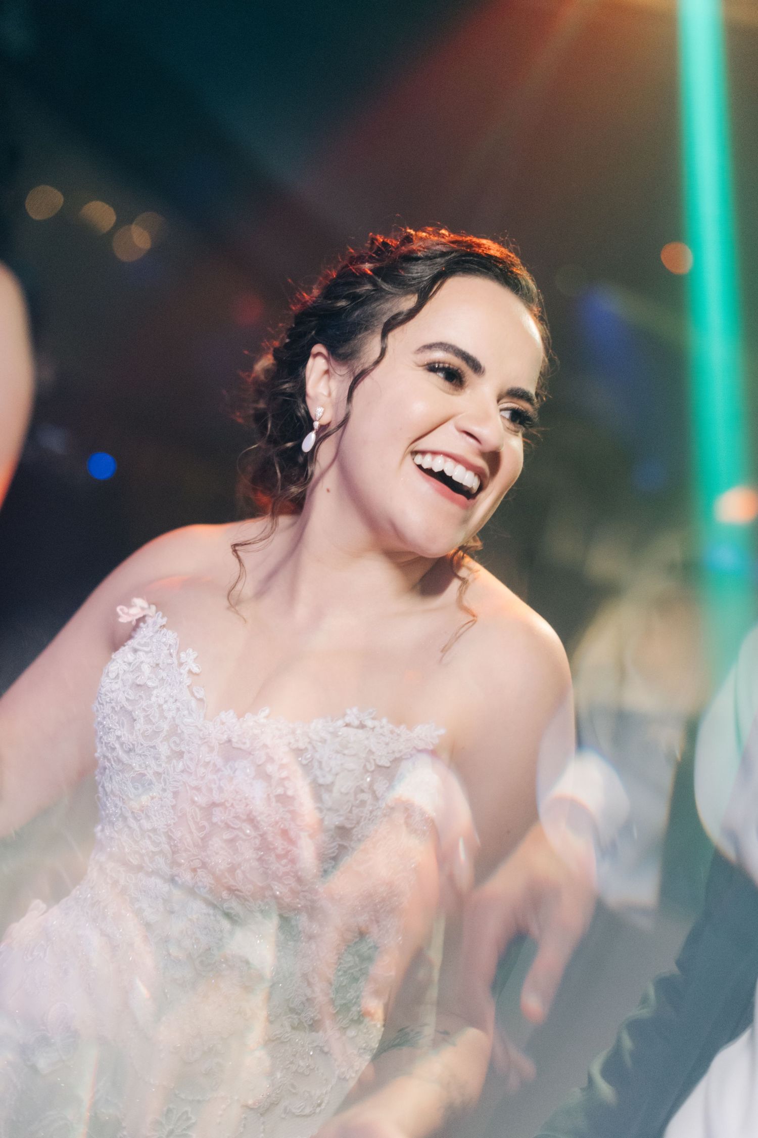 Close-up of joyful laughter during a wedding celebration with teal lighting.