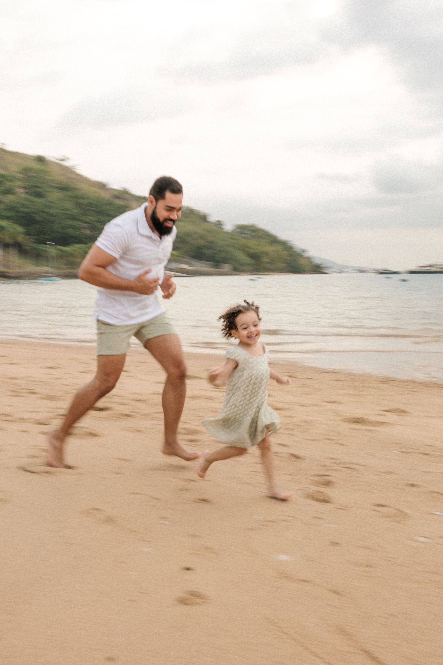 Playful chase scene on a sandy beach with mountains visible in the background.