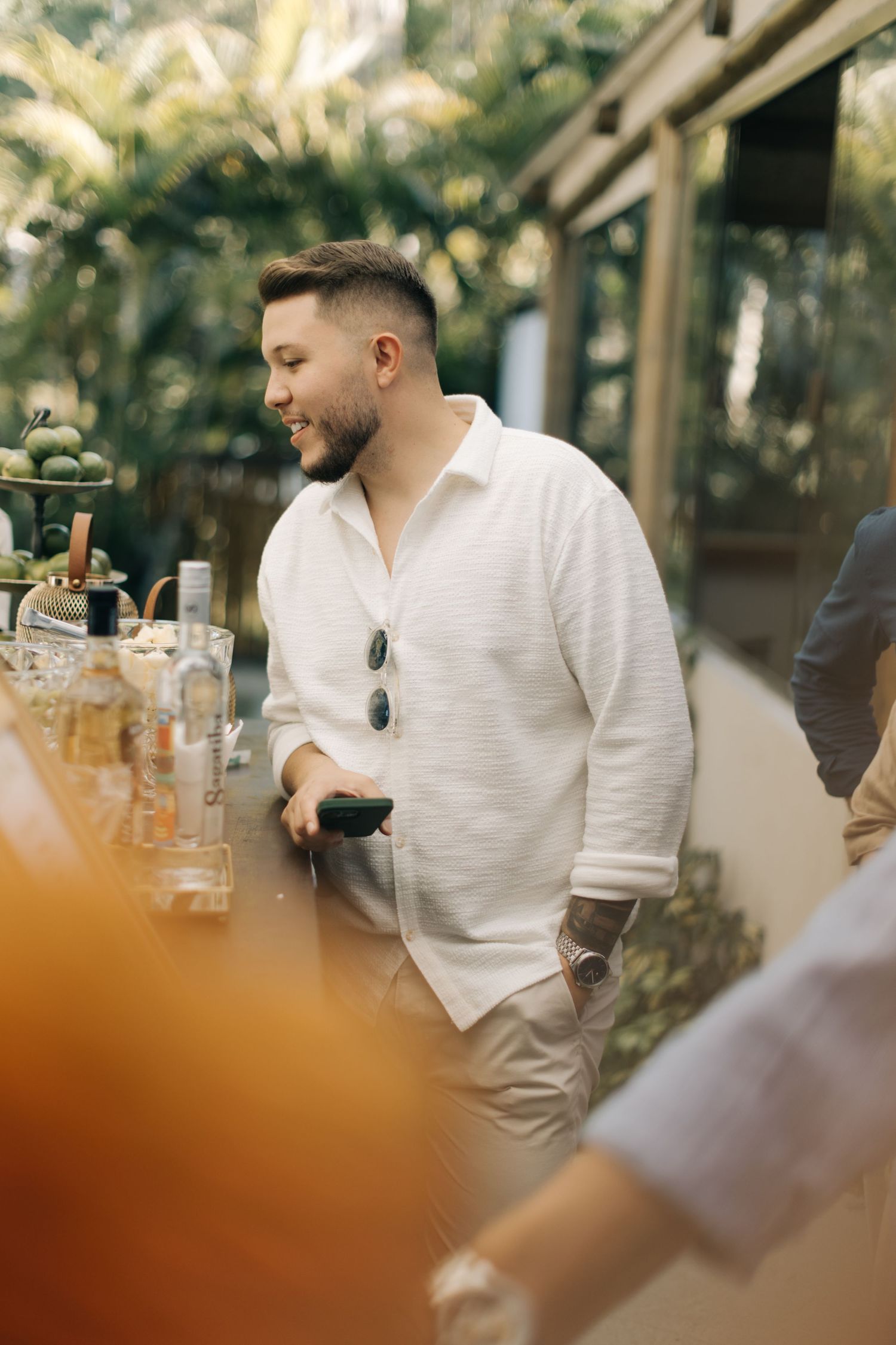 Guests enjoy refreshments at an outdoor wedding reception under natural lighting.