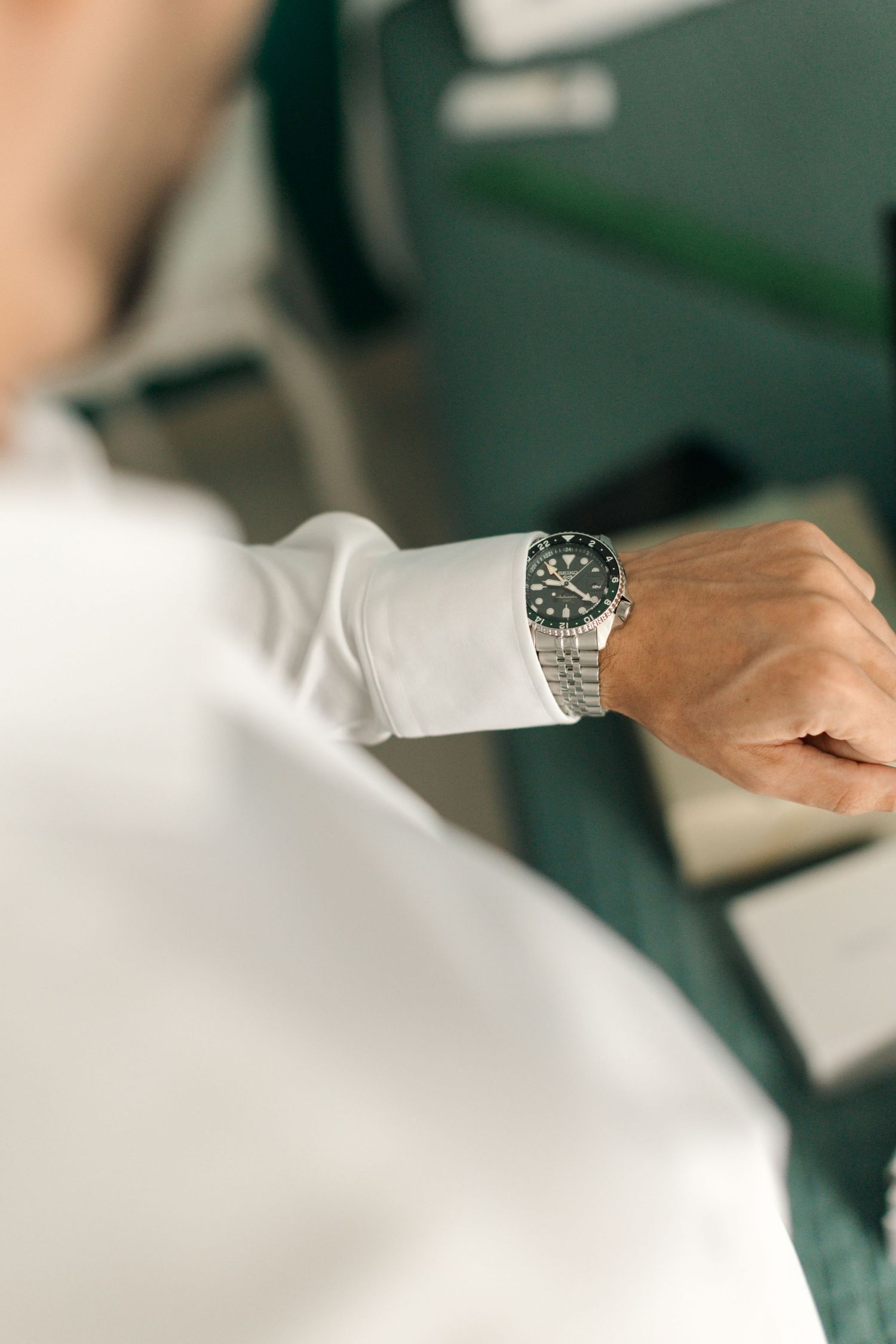 Detailed shot of luxury watch worn on wrist with white shirt sleeve.